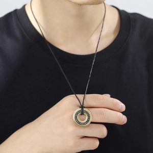 Dettaglio del ciondolo con rune nordiche oro e nero con cordino in pelle intrecciata
