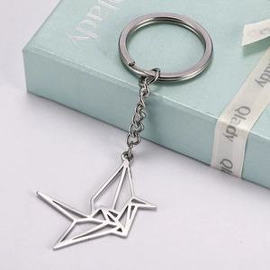 Detailed macro view of an origami crane stainless steel keychain pendant on gift box