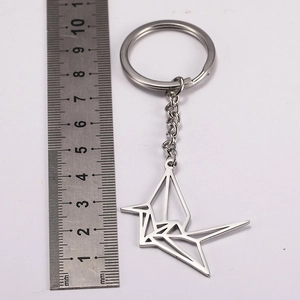 Polished stainless steel origami crane keychain with measurement ruler on white background