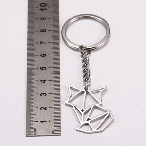 Detailed macro view of a geometric fox keychain in stainless steel next to a measuring ruler