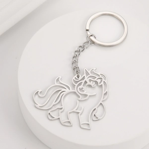 Detailed view of cutout unicorn keychain in polished silver stainless steel on white pedestal