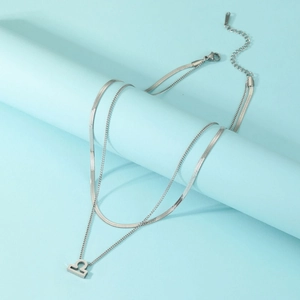 Détail d'un collier argenté à deux couches avec chaîne serpent et pendentif Balance