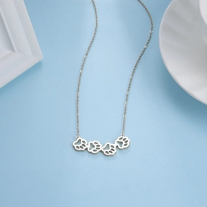 Detail view of silver hollow animal paw pendants on a delicate stainless steel necklace