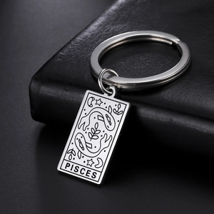 Macro shot of stainless steel keychain with Pisces engraving on black leather