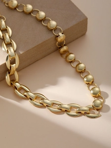 Dettaglio della collana d'oro a doppia catena con dischi opachi e maglie lucide