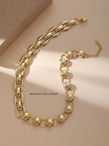 Dettaglio di una collana dorata chunky con design asimmetrico e chiusura a moschettone
