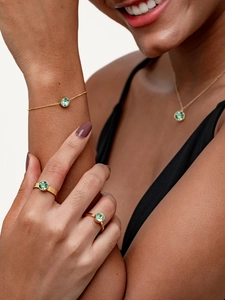 Nahaufnahme eines eleganten Gold-Schmucksets mit quadratischem grünem Zirkonia-Anhänger