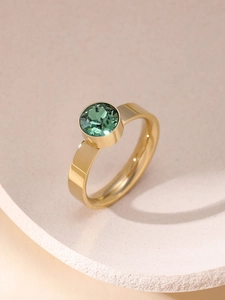 Nahaufnahme eines goldenen Rings mit rundem grünem Zirkonia in einer Zargenfassung