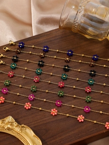 Details bunter Perlenblumen-Armbänder mit Goldkette auf einem Holztablett