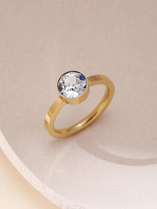 Makroaufnahme eines minimalistischen Goldrings mit Zirkonia-Zargenfassung auf Tablett