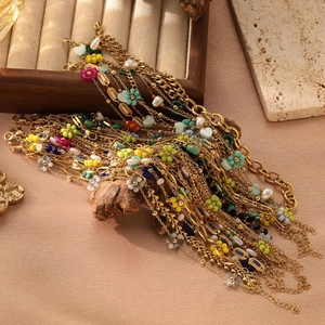 Detail of bohemian gold chains with colorful floral resin charms and white pearls