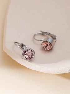 Nahaufnahme von rosa Kristallohrringen mit silbernen Klappbügeln auf neutralem Grund