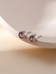 Nahaufnahme minimalistischer rosa Zirkon-Ohrringe mit Silberfassung auf strukturiertem Stein