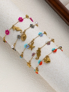 Detail of five gold ocean-themed bracelets with colorful beads, starfish and seahorse charms