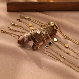 Set de pulseras de acero de titanio dorado con dijes de corazón sobre madera natural