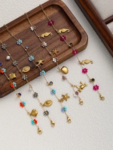 Detailed macro view of four gold-finish ocean-themed charm bracelets with colorful beads