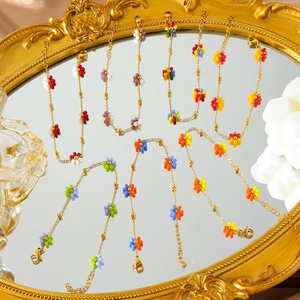 Detail von bunten Perlen-Blumenarmbändern auf Goldspiegel mit Karabinerverschluss