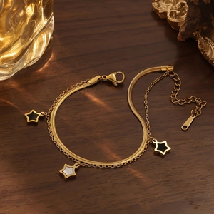 Detalle de una pulsera dorada de doble capa con estrellas y etiqueta grabada S.STEEL