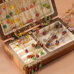 Collier élégant en or avec pendentifs fleurs en perles colorées dans une boîte en bois
