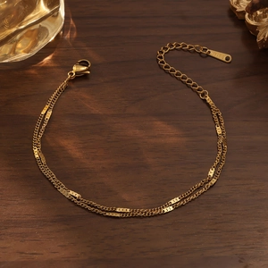 Detalle de pulsera de doble capa en acero dorado con cierre de langosta y grabado