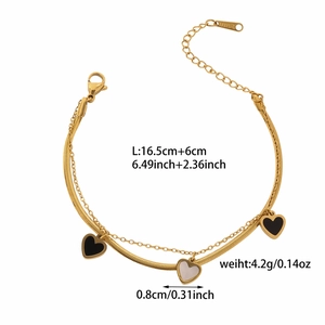 Detalle de la pulsera de doble capa dorada con dijes de corazones en negro y blanco