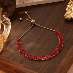 Detailaufnahme des goldenen Schlangenkette-Armbands mit roten Baguette-Edelsteinen