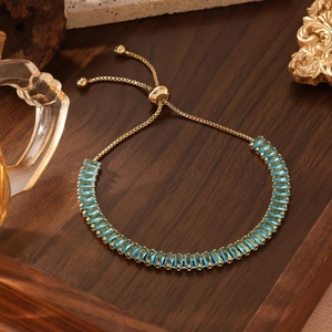 Nahaufnahme eines vergoldeten verstellbaren Armbands mit blauen Zirkonia im Baguetteschliff