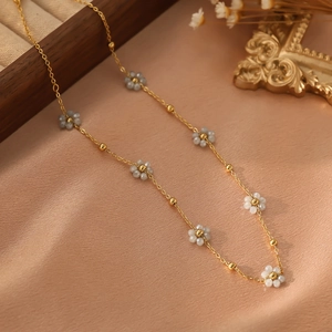 Détail de l'élégant collier en acier inoxydable doré avec de petites fleurs en perles