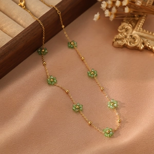 Détail d'un collier doré avec fleurs en perles vertes sur une boîte à bijoux vintage
