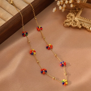 Détail du collier en chaîne dorée avec fleurs en perles colorées sur soie champagne