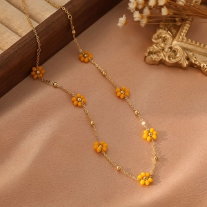 Détail de perles fleur jaune et chaîne dorée sur fond de soie pour collier élégant