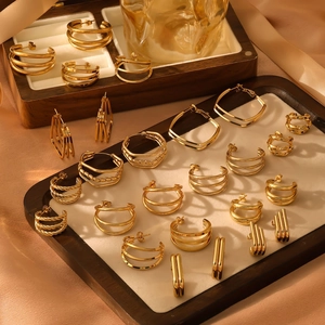 Golden geometric square and C-shaped earrings set displayed on a wooden jewelry tray