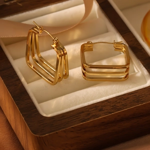 Three-layer square geometric metal hoop earrings in gold finish on velvet display