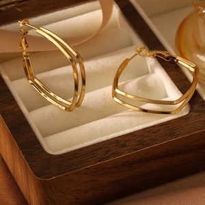 Macro shot of gold-plated double-layer geometric earrings in a luxury wooden box