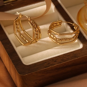 Detail of layered geometric C-shaped earrings with twisted texture in gold finish