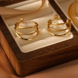 Detailed view of gold triple-layered C-shape hoop earrings on a velvet jewelry box
