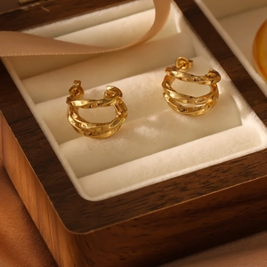 Close-up of golden triple-layered twisted rope hoop earrings inside a jewelry box