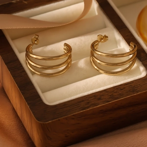 Close-up of triple-layered golden hoop earrings on white velvet in a wooden box