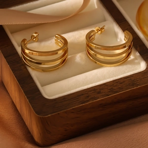 Macro shot of gold-plated triple hoop earrings resting in a premium velvet jewelry box