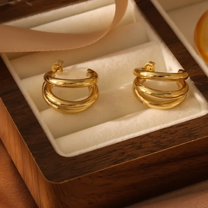 Close-up of golden triple-layered hoop earrings displayed in a luxury wooden jewelry box