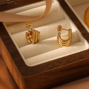 Macro detail of gold geometric C-shaped hoop earrings inside a velvet jewelry box