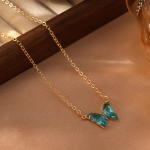 Vue détaillée du pendentif papillon doré avec cristaux bleus et petits diamants étincelants