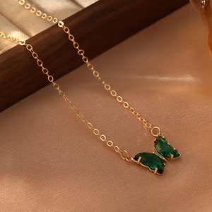 Détail d'un pendentif papillon doré avec cristaux verts et petits diamants blancs