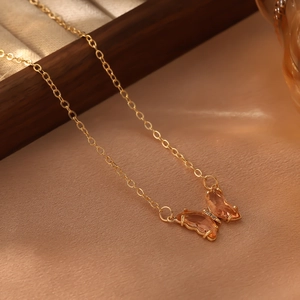 Détail macro du pendentif papillon en cristal ambre avec chaîne dorée et zircons