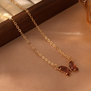 Détail du pendentif papillon avec cristaux marron et chaîne dorée élégante
