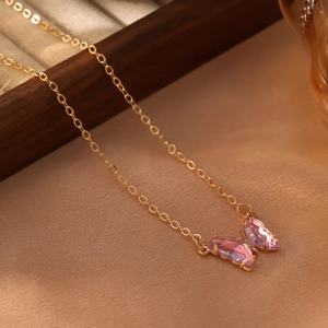 Vue macro du pendentif papillon en cristal rose serti sur une chaîne dorée