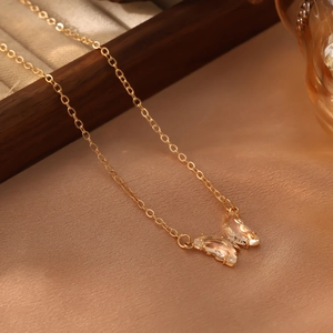Détail du pendentif papillon en cristal champagne sur une chaîne dorée et boîte à bijoux