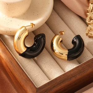 Detail of C-shaped gold and black enamel earrings in a luxury wooden jewelry box