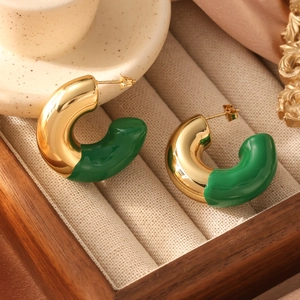 Detail shot of chunky gold-tone C-shaped earrings with vibrant green enamel finish