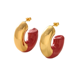 Macro detail of C-shaped hoop earrings with gold metal and red enamel finish